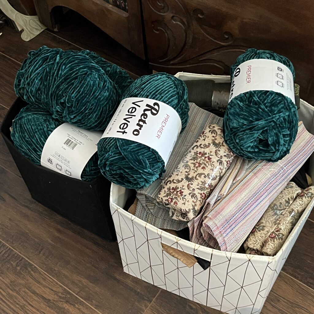 Two fabric bins full of miscellaneous yarn and rolls of fabric scraps